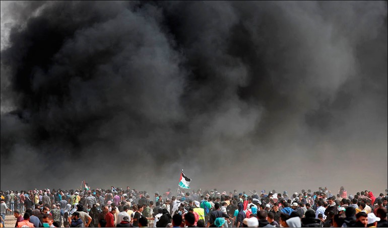 آلاف الفلسطينيين يتظاهرون بالقرب من السياج الحدودي مع إسرائيل جنوب غزة في جمعة «حرق العلم الإسرائيلي ورفع العلم الفلسطيني».. وفي الإطار فلسطينيون يحرقون علم الاحتلال أمس			   (أ.ف.پ)