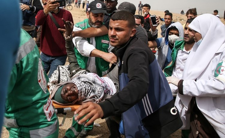 فلسطينيون يسعفون متظاهرة بعد اصابتها برصاص الاحتلال على حدود غزة امس(ا.ف.پ) ﻿