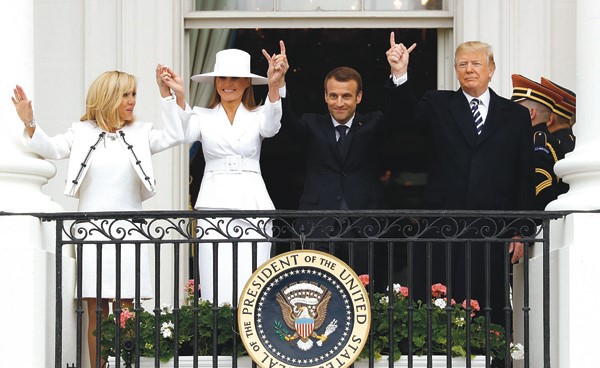 الرئيس الأميركي دونالد ترامب وعقيلته ميلانيا والرئيس الفرنسي ايمانويل ماكرون وعقيلته بريجيت يرفعون أيديهم على شرفة ترومان خلال الاستقبال الرسمي في البيت الأبيض          (رويترز)