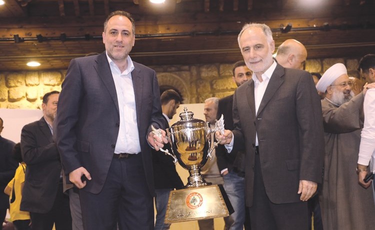 محمد فنيش مع رئيس نادي العهد تميم سليمان وأمامهما كأس بطولة الدوري﻿