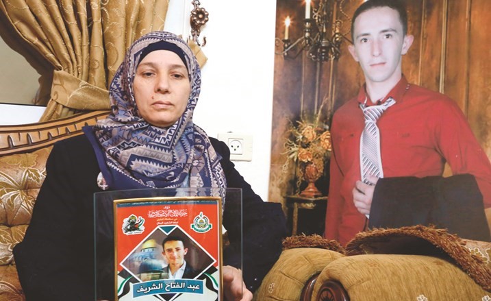 رجا تحمل صورة ولدها الشهيد عبد الفتاح الشريف الذي قتله جندي إسرائيلي وهو جريح	(أ.ف.پ)﻿