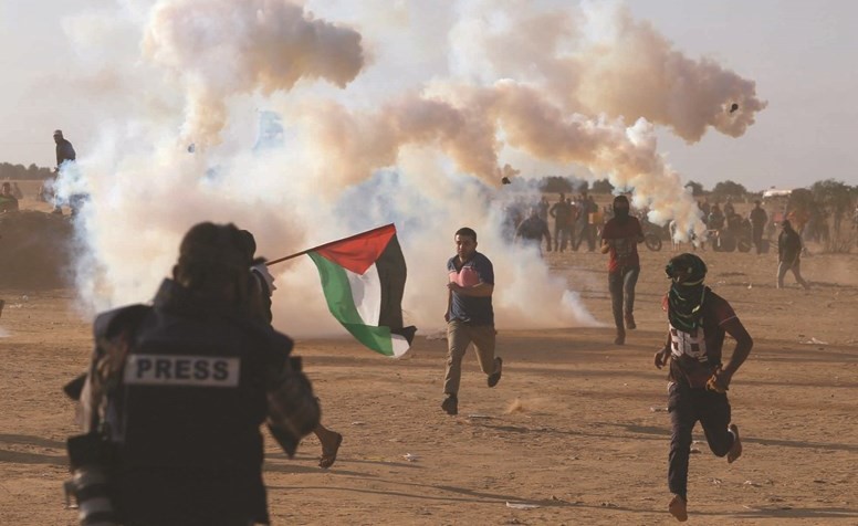 فلسطينيون يحاولون تجنب قنابل الغاز الإسرائيلية في غزة-(رويترز)﻿