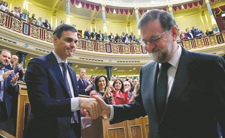 رئيس الوزراء الإسباني السابق ماريانو راخوي يصافح رئيس الوزراء الجديد بيدرو سانشيز في البرلمان امس- (أ.ف.پ)﻿