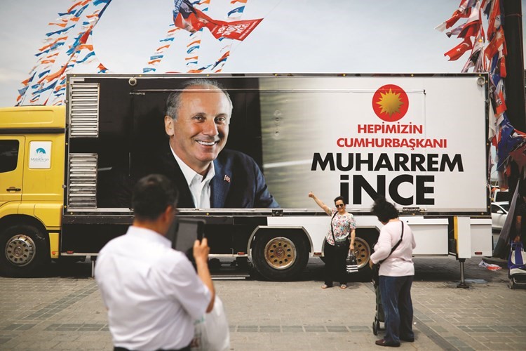 سيدة تركية تتصور امام حافلة تحمل صورة مرشح المعارضة الرئيسية محرم اينجه في اسطنبول﻿