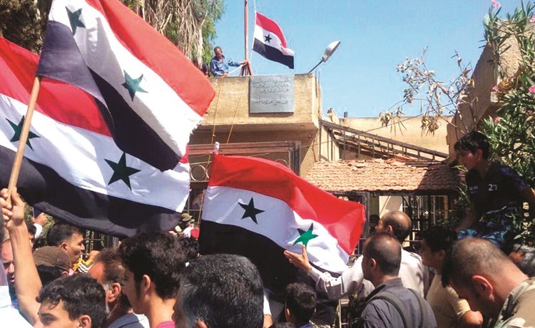 صورة نشرتها وكالة الأنباء العربية السورية الرسمية (سانا) لرفع العلم قرب مكتب البريد جنوب درعا أمس	 (أ.ف.پ)﻿
