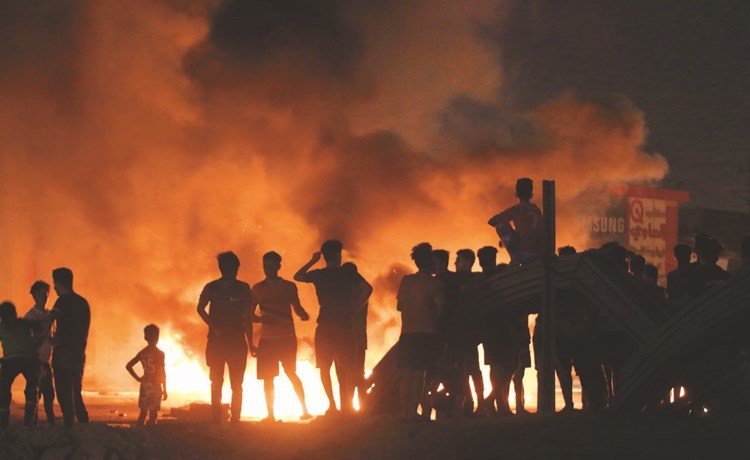 محتجون عراقيون يضرمون النيران في اطارات السيارات خلال الاحتجاجات في البصرة مساء أمس الأول	(أ.ف.پ)﻿