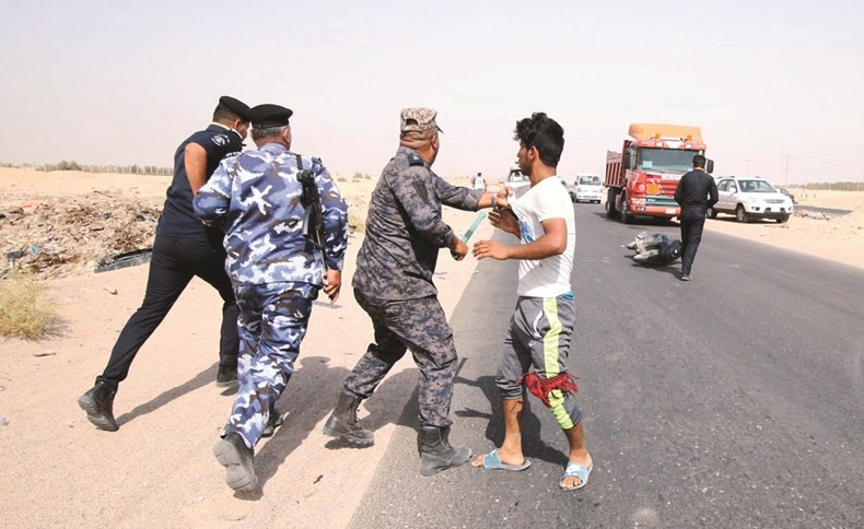 رجال الامن العراقي يستخدمون الهراوات خلال اعتقال احد المحتجين امام حقل الزبير امس	 (رويترز)﻿