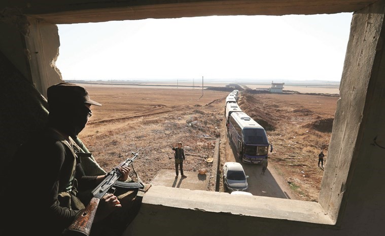 عنصر من هيئة تحرير الشام يراقب دخول الحافلات الى بلدتي كفريا والفوعة لاجلاء المدنيين والمسلحين	(ا.ف.پ)﻿