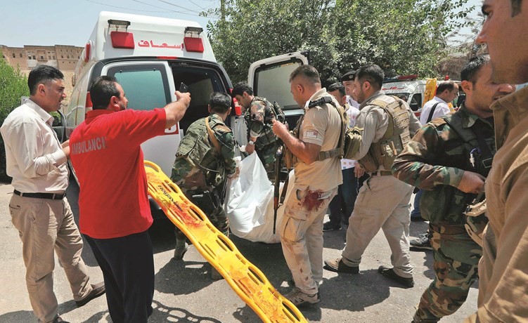عناصر من القوات الكردية ينقلون جثة احد المسلحين بعد انتهاء هجوم أربيل أمس (ا.ف.پ)﻿