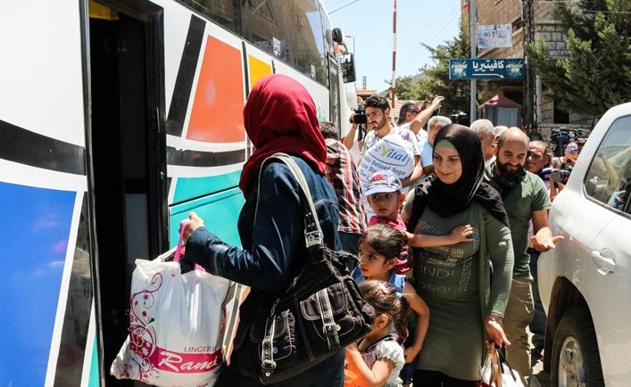 لاجئون سوريون يستقلون الحافلات التي ستعيدهم الى سوريةعند نقطة المصنع الحدودية(أ.ف.ب.)﻿