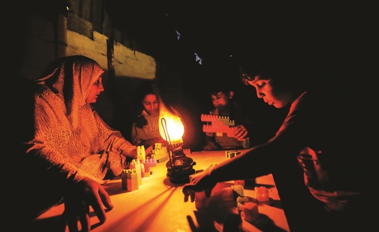 عائلة فلسطينية تستضيء بقنديل الكاز في خان يونس بقطاع غزة	(ا.ف.پ) ﻿