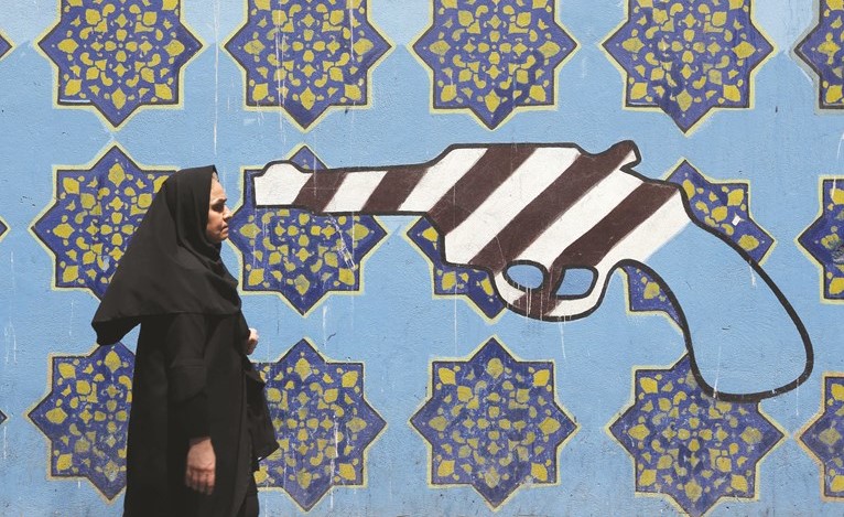 ايرانية تسير بجانب لوحة جدارية على حائط السفارة الاميركية السابقة في طهران أمس(أ.ف.پ)﻿