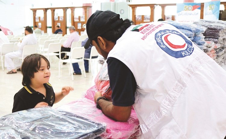 متطوعو جمعية الهلال الأحمر يوزعون حقائب مدرسية على أطفال الأسر المحتاجة في الكويت ﻿
