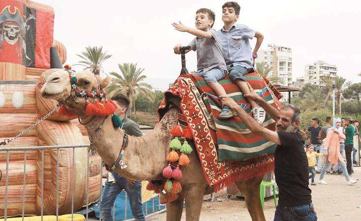أطفال لاجئون سوريون يركبون الجمل ويلعبون في احدى حدائق بيروت	(أ.ف.پ)﻿