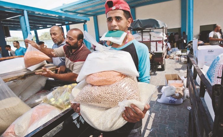 فلسطينيون بمعسكر رفح جنوبي قطاع غزة يحصلون على حصتهم من المواد الغذائية امس	(ا.ف.ب)﻿