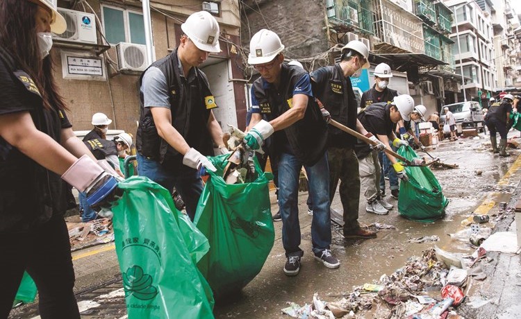 رجال الشرطة ينظفون الحطام الناتج عن الإعصار من أحد شوارع ماكاو -(أ.ف.پ)﻿
