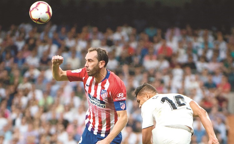 مدافع أتلتيكو دييغو غودين يبعد الكرة قبل لاعب ريال مدريد كاسيميرو (أ.ف.پ) ﻿
