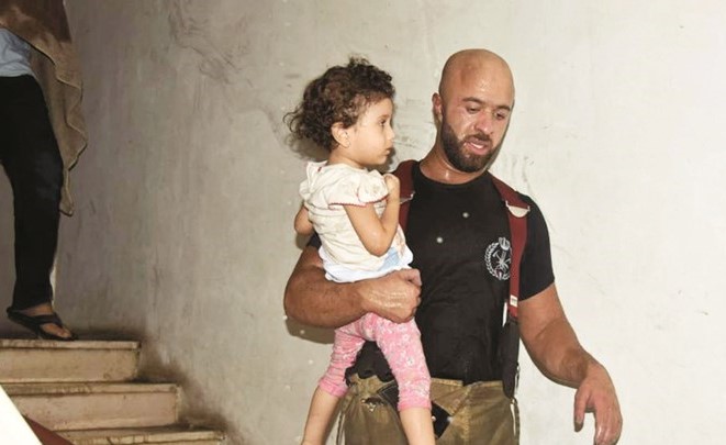أحد رجال فرقة الإخلاء ينقذ طفلة ﻿