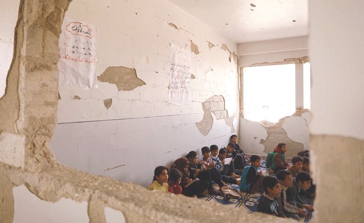 تلاميذ سوريون يدرسون في مدرسة دمرها القصف في مدينة مورك التي تسيطر عليها المعارضة في حماة	(ا.ف.پ)﻿