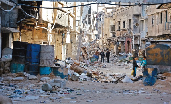 سوريون يمشون وسط الحطام في حي التضامن الدمشقي (أ ف ب)