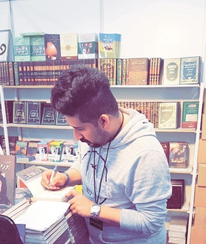 حسين المتروك أثناء توقيع نسخ من الكتاب في المعرض﻿