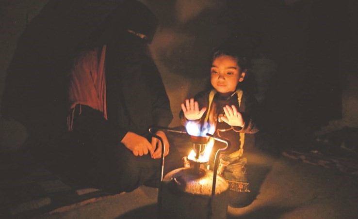 سيدة سورية لاجئة من البوكمال وابنتها ذات الاربع سنوات تتدفآن علىوابور الكاز في غرفتها في قبو احد الابنية في الباب بريف حلب (أ.ف.پ)﻿