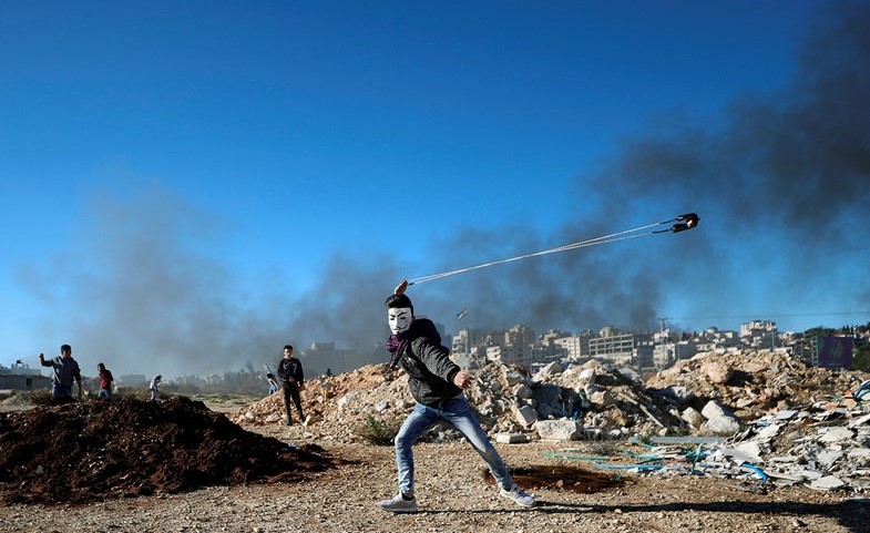 متظاهر فلسطيني يلقي الحجارة على قوات الاحتلال بالقرب من رام الله امس	(رويترز)﻿