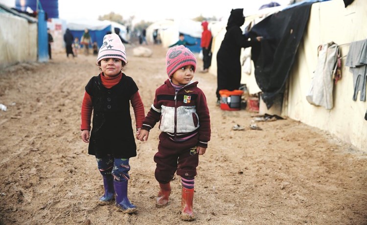 أطفال سوريون يسيرون في مخيم للنازحين بالقرب من الحدود مع تركيا في محافظة حلب	(أ.ف.پ)﻿
