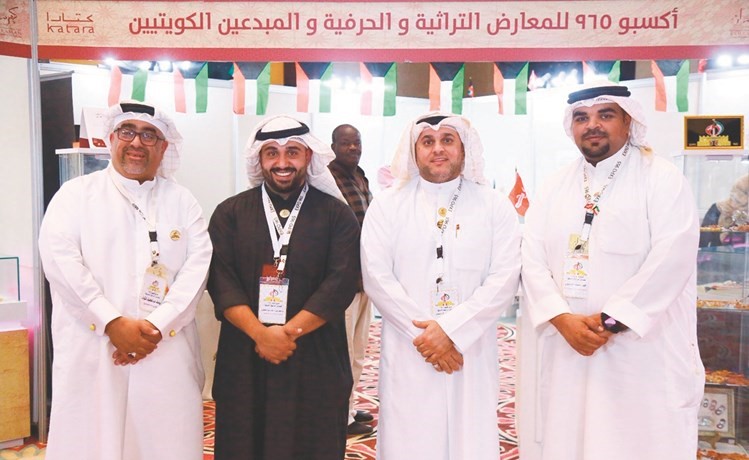 الباحث محمد كمال يتوسط عددا من الحرفيين الكويتيين في جناح الكويت بمعرض كتارا الأول لمسابيح الكهرمان﻿