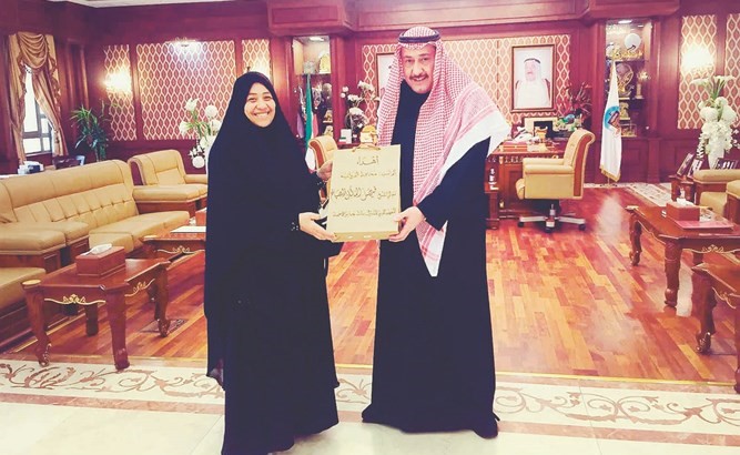 الشيخ فيصل الحمود يتلقى الرزنامة من المعلمة سحر محمد﻿