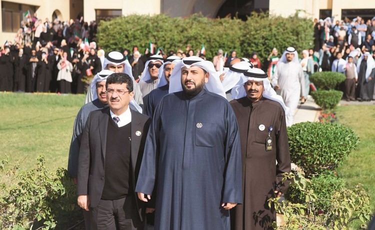 الشيخ د.باسل الصباح ود.مصطفى رضا يتقدمان موظفي الصحة خلال الاحتفال بمراسم رفع العلم- (محمد هاشم)﻿