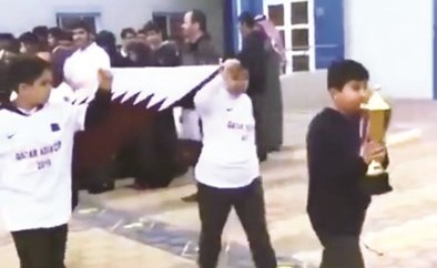 الطلبة يحملون العلم القطري في الطابور﻿