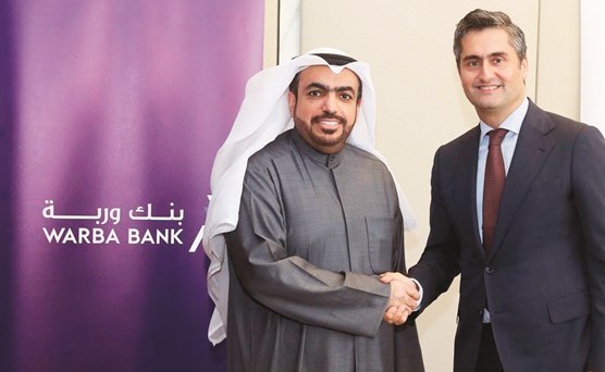 شاهين الغانم مصافحا طارق محمود على هامش توقيع الاتفاقية﻿