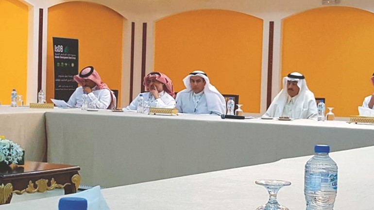 الأمين العام خلال مشاركته بفعاليات الورشة وعن يساره د.بندر بن محمد حمزة رئيس مجموعة البنك الإسلامي للتنمية وعن يمينه مستشار أمير منطقة المدينة المنورة﻿