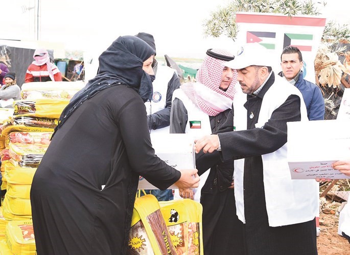 علي الدقباسي يقدم مساعدة الهلال الاحمر ويبدو السفير عزيز الديحاني﻿