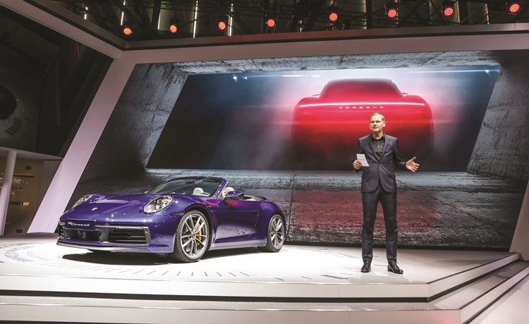 أوليفر بلوم إلى جانب 911 كابريوليه الجديدة بعد الكشف عنها في معرض جنيف للسيارات﻿