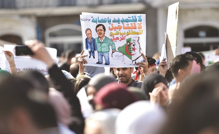 محتجون يرفعون لافتات تؤكد إصرارهم على تغيير النظام خلال تظاهرة في العاصمة الجزائرية أمس 	(رويترز)﻿