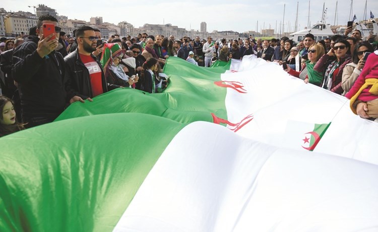 متظاهرون يرفعون العلم الجزائري ويطالبون بتنحي الرئيس عبدالعزيز بوتفليقة في فرنسا امس الاول	(أ.ف.پ)﻿