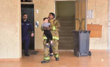 أحد رجال الإطفاء يحمل طفلا﻿