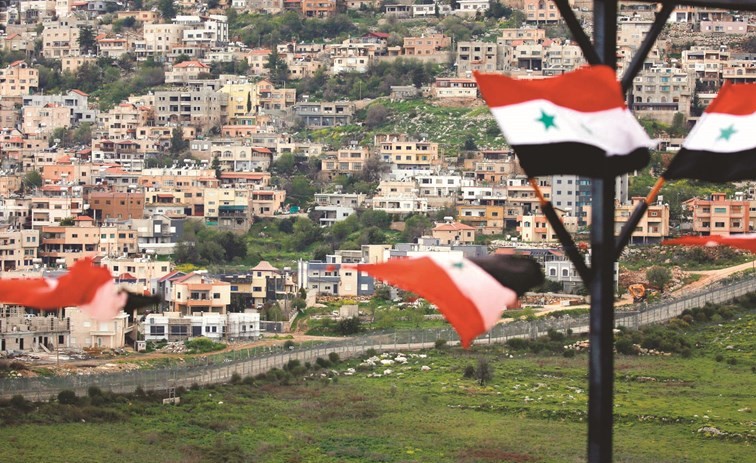 أعلام سورية ترتفع في بلدة عين التينة المقابلة لبلدة مجدل شمس في الجزء المحتل من الجولان	 (رويترز)﻿