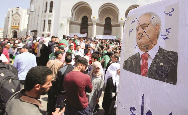 الطلاب المتظاهرون يحملون صورة لرئيس المجلس الدستوري المستقيل الطيب بلعيز خلال احتجاجهم في العاصمة الجزائر امس(رويترز)﻿