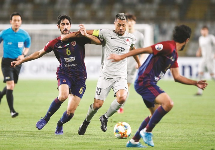 لاعب الريان تاباتا يحاول المرور من مدافعي الوحدة الإماراتي﻿