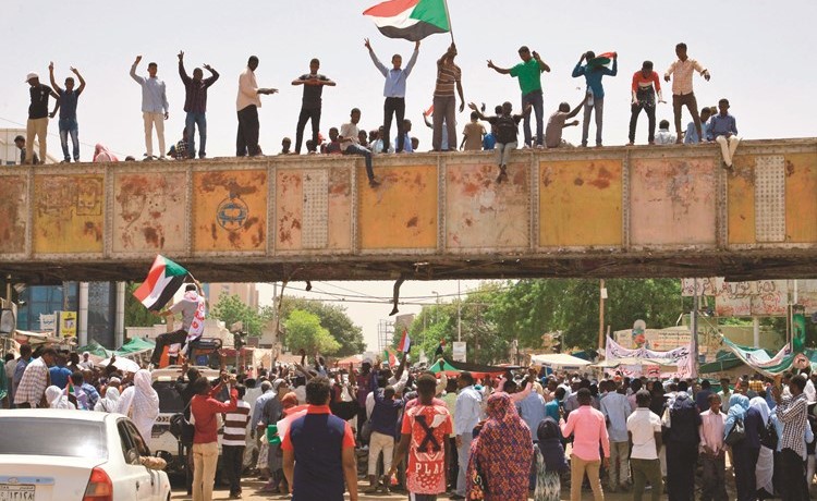 المتظاهرون يلوحون بالعلم السوداني خلال اعتصامهم خارج مقر الجيش في الخرطوم امس	(أ.ف.پ)﻿