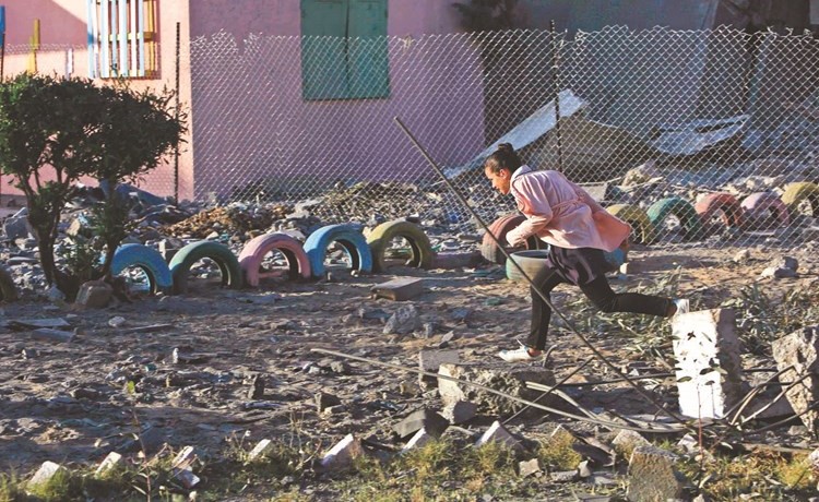 طالبة فلسطينية تركض في فناء مدرسة مجاورة لمبنى دمره الاحتلال في غزة امس	(أ.ف.پ)﻿