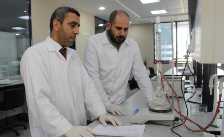  الباحث مياس الريماوي (يسار) داخل معمله في جامعة البترا برفقة أحد زملائه (الجزيرة نت)