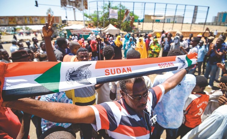 سوداني يحمل علم بلاده خلال الاحتجاج خارج مقر الجيش في العاصمة الخرطوم أمس	 		(أ.ف.پ)﻿