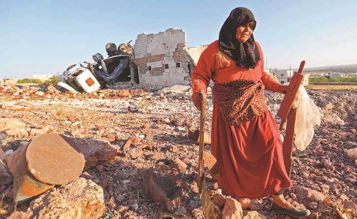 سيدة تجمع بقايا من منزلها الذي دمر في قصف كفرنبل	(أ.ف.پ)﻿