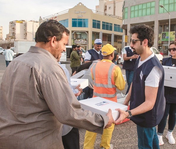 المتطوعون من موظفي بنك الكويت الوطني أثناء توزيع وجبات الإفطار﻿