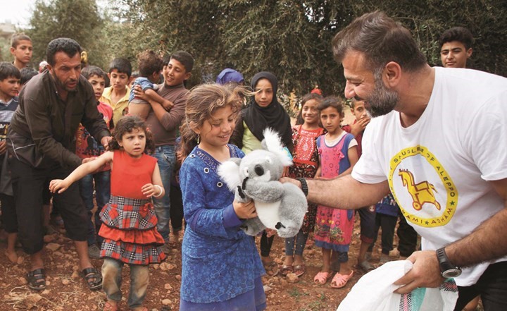 متطوع سوري يعيش في فنلندا ويطلق على نفسه مهرب الدمى من حلب يوززع الالعاب على اطفال المهجرين في مخيم قرب عقربات في ادلب (أ.ف.پ)﻿