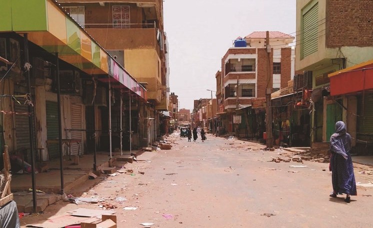 سيدة سودانية تسير بجوار متاجر مغلقة في أم درمان في اليوم الأول للعصيان المدني امس	(أ.ف.پ)﻿